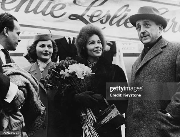 Actress and dancer Leslie Caron is greeted by a bouquet of flowers and MGM Chief Beerman as she arrives for the premiere of the film 'Gigi',...