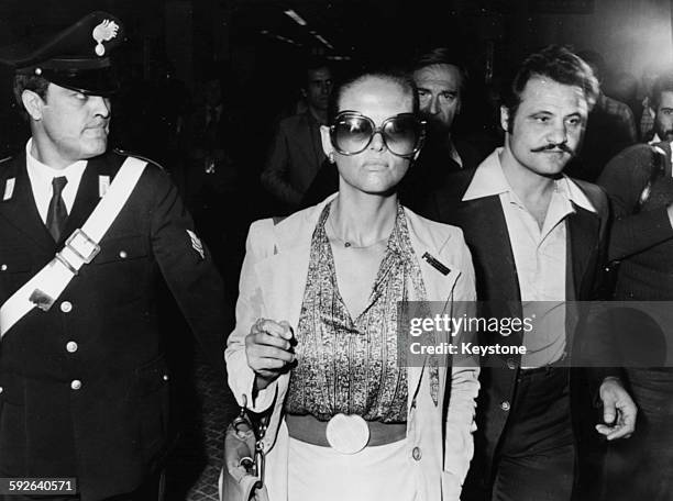 Actress Claudia Cardinale wearing sunglasses as she is escorted to court, where director Pasquale Squitieri is appearing on charges of firing shots...