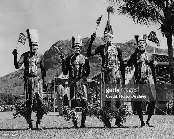 Australian aborigines from Palm Island wearing traditional clothing but waving Union Jack flags, welcoming Queen Elizabeth II during a visit to...