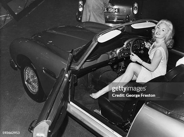 Actress and model Barbara Roscoe at the wheel of the new Aston Martin DB5 car, at the Motor Show in Earls Court, London, October 15th 1963.