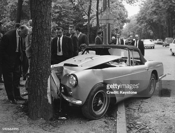 The Ferrari 250 GT car of diplomat and racing driver Porfirio Rubirosa crashed in to a chestnut tree, being viewed by a group of men in suits after...