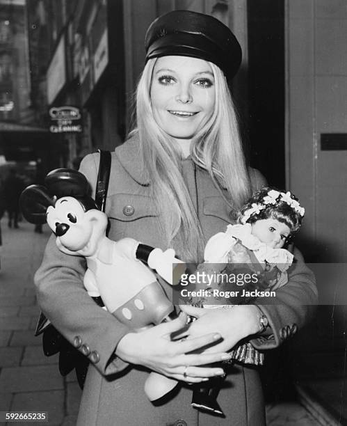 Miss World winner Eva Rueber-Staier holding a Mickey Mouse doll and a Czech doll as she prepares to return home to Austria following the competition,...