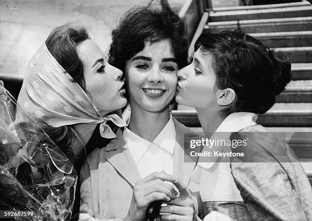 American actress Millie Perkins, star of the film 'The Diary of Anne Frank', being kissed on the cheeks by French actresses Pascale Audret and Edith...