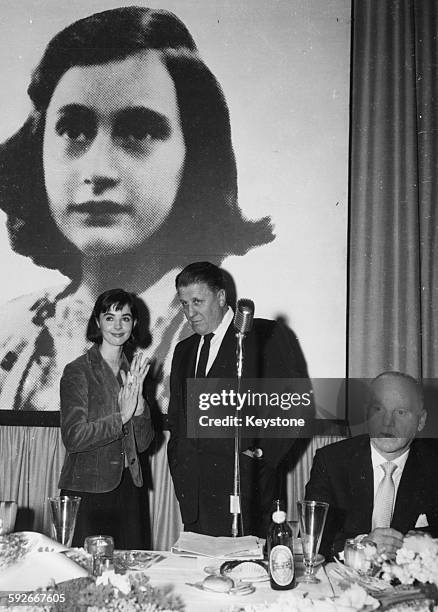 Actress Millie Perkins talking to producer George Stevens in front of a picture of holocaust victim Anne Frank, at a reception for their film 'The...