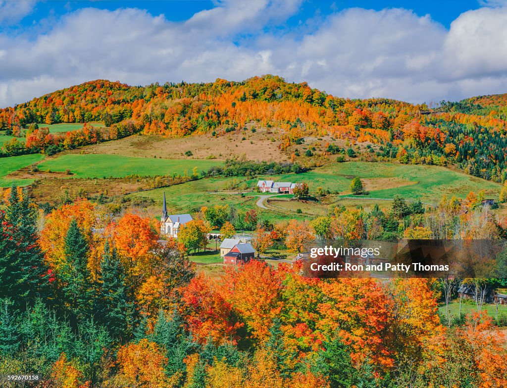 Peak autumn sugar maples with village in Vermont