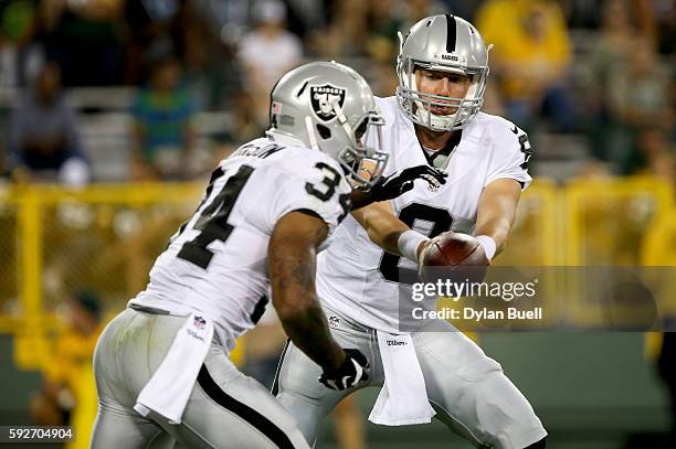 Connor Cook of the Oakland Raiders hands the ball off to George Atkinson III in the fourth quarter of a preseason game against the Green Bay Packers...