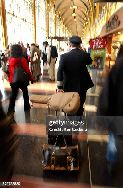 Pilot walks briskley through Reagan National Airport in Arlington, Virginia., as travelsers wait in long lines before having to pass through...