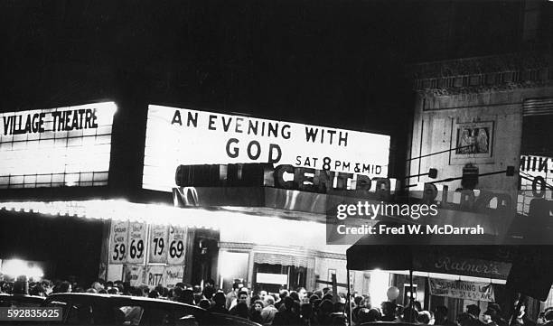 View across Second Avenue of a crowd of people under the marquee for the Fillmore East, which advertises 'An Evening with God,' New York, New York,...