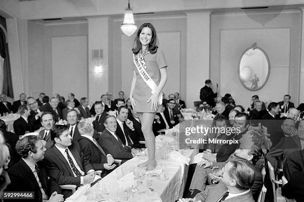 Walking along the table top - the only woman amongst the 150 guests, Jacquie Perrin "Miss Canada" gives the guests a preview of her "Miss World"...