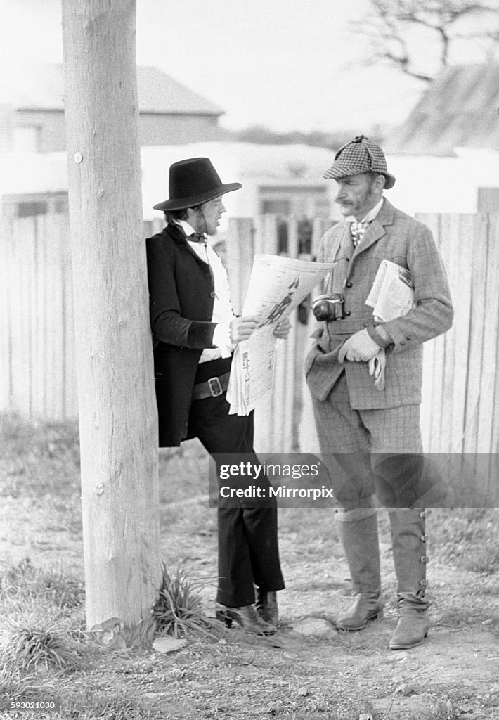 Rolling Stones singer Mick Jagger relaxes by reading a newspaper as he talks to Australian actor Ronald Golding in a bre