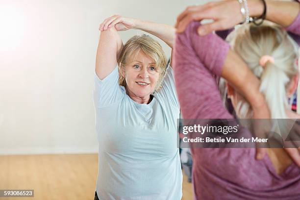 senior woman follows teacher in exercise class. - mature women exercise stock pictures, royalty-free photos & images