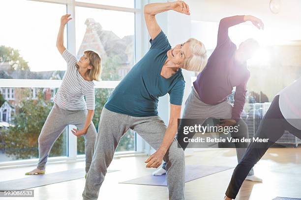 seniors exercising in yoga class indoors. - woman jogging pants stock pictures, royalty-free photos & images