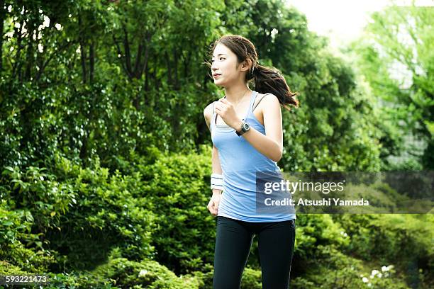 young woman jogging in park - hemden stockfoto's en -beelden