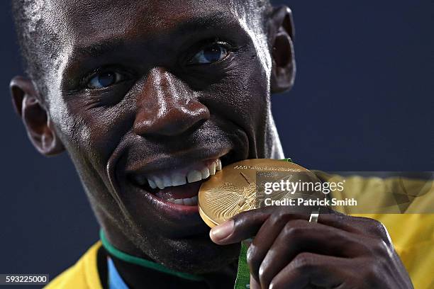 Gold medalist Usain Bolt of Jamaica bites his gold medal during the medal ceremony for the Men's 4 x 100 meter Relay on Day 15 of the Rio 2016...