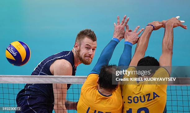 Italy's Ivan Zaytsev spikes the ball past Brazil's players during the men's Gold Medal volleyball match between Italy and Brazil at the Maracanazinho...