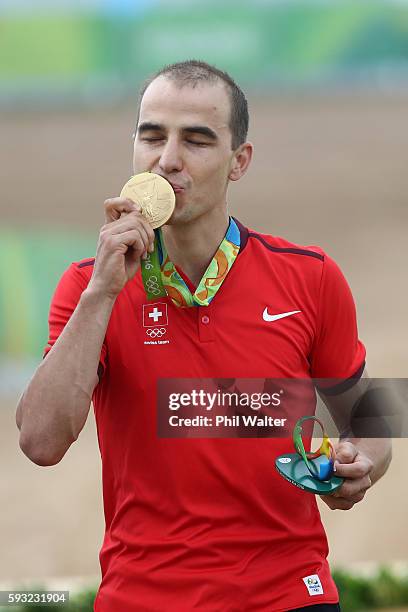 Nino Schurter of Switzerland celebrates winning gold during the medal ceremony for Men's Cross-Country on Day 16 of the Rio 2016 Olympic Games at...