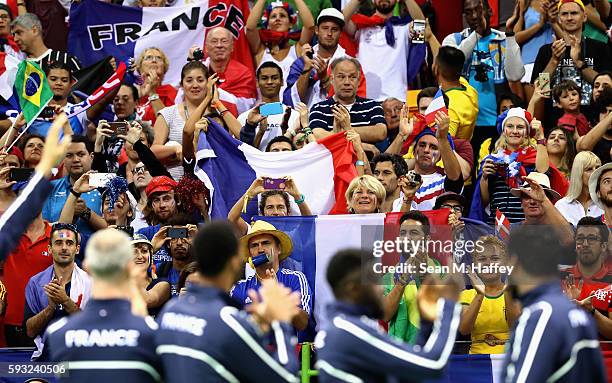 Fans cheer as team France pose during the medal ceremony for Men's Handball after winning the silver medal on Day 16 of the Rio 2016 Olympic Games at...