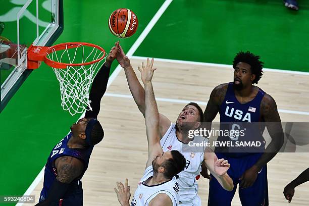 S forward Carmelo Anthony jumps for a rebound with Serbia's power forward Milan Macvan and Serbia's centre Vladimir Stimac during a Men's Gold medal...