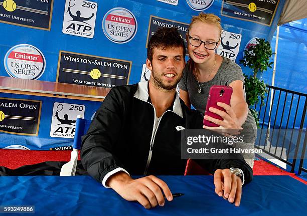 Jiri Vesely of the Czech Republic poses for a selfie with a fan as he signs autographs during the Winston-Salem Open at Wake Forest University on...