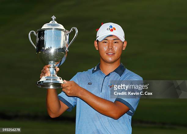 Si Woo Kim of South Korea poses with the trophy after winning the final round of the Wyndham Championship at Sedgefield Country Club on August 21,...