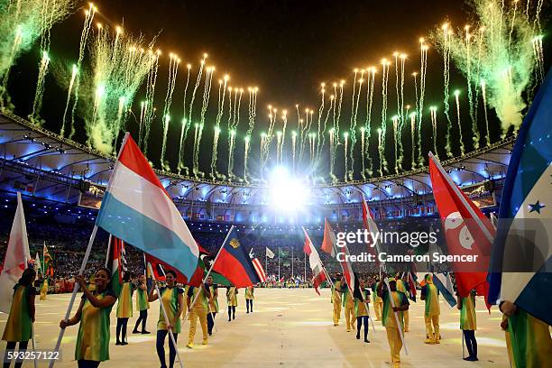 Athletes walk during the 'Heroes of the Games' segment as fireworks explode during the Closing Ceremony on Day 16 of the Rio 2016 Olympic Games at...