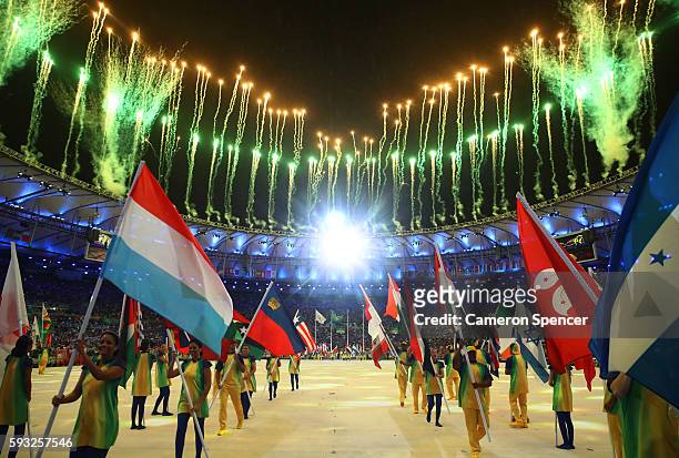 Athletes and volunteers walk during the 'Heroes of the Games' segment as fireworks explode during the Closing Ceremony on Day 16 of the Rio 2016...