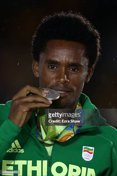Silver medalist Feyisa Lilesa of Ethiopia stands on the podium during the medal ceremony for the Men's Marathon during the Closing Ceremony on Day 16...