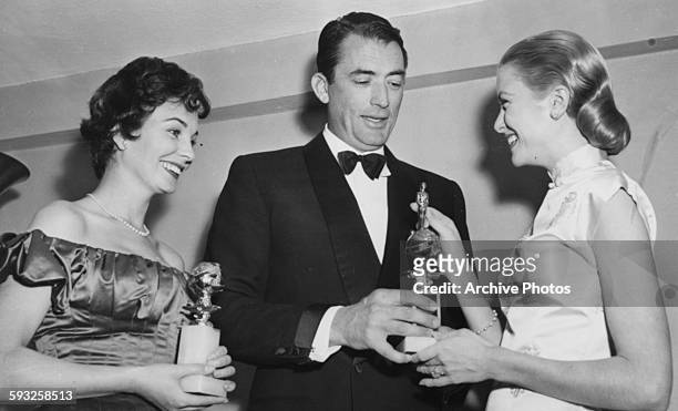 Actress Grace Kelly receiving her 'Henrietta' award from Gregory Peck, with actress Jean Simmons, at the Foreign Press Awards, or the Golden Globes,...