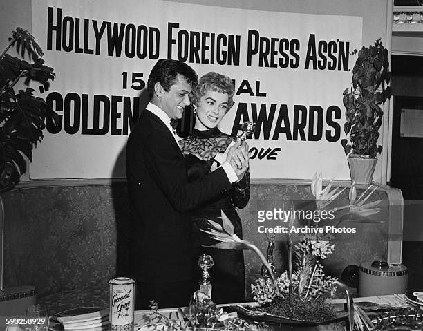 Actor Tony Curtis showing his 'Henrietta' award to his wife, actress Janet Leigh, at the Foreign Press Awards, or the Golden Globes, in Hollywood,...