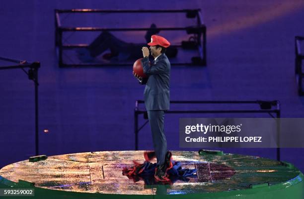 Japanese Prime Minister Shinzo Abe, dressed as Super Mario, holds a red ball during the closing ceremony of the Rio 2016 Olympic Games at the...