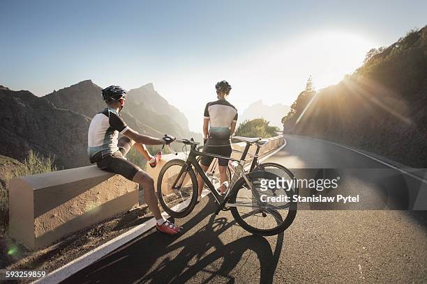 two cyclists watching at sunset in mountains - ciclismo fotografías e imágenes de stock