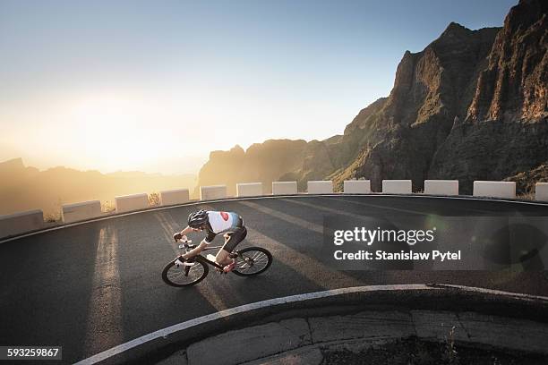 cyclists making a turn in mountains at sunset - bicycle top view stock-fotos und bilder