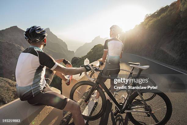 couple of cyclists enjoying sunset in mountains - cycling vest stock pictures, royalty-free photos & images