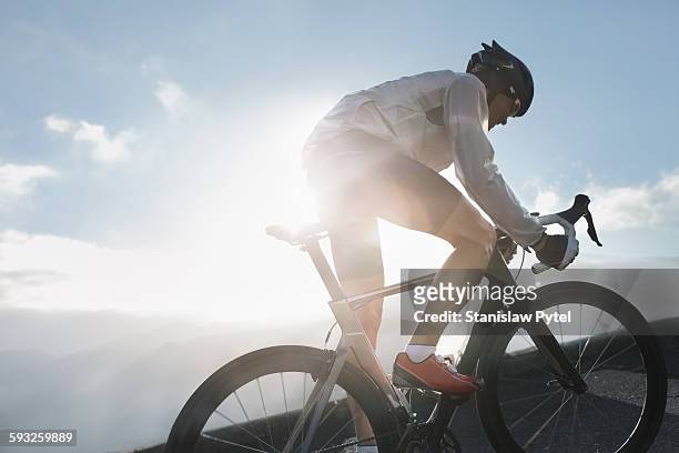 silhouette of cyclist riding up in high mountains - ciclismo fotografías e imágenes de stock