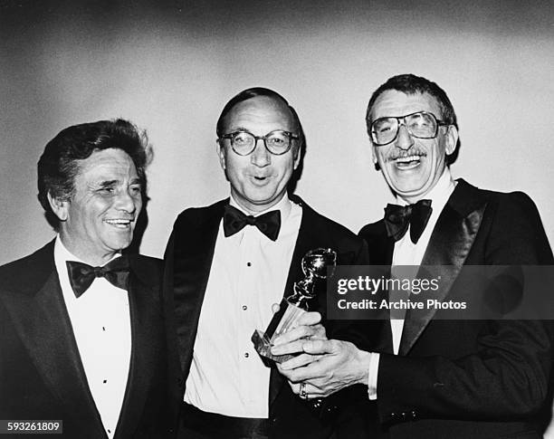 Writer Neil Simon holding his Best Screenplay Award, with actor Peter Falk and director Herbert Ross , at the Golden Globe Awards, January 1978.