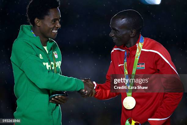 Silver medalist Feyisa Lilesa of Ethiopia and gold medalist Eliud Kipchoge of Kenya shake hands during the medal ceremony for the Men's Marathon...