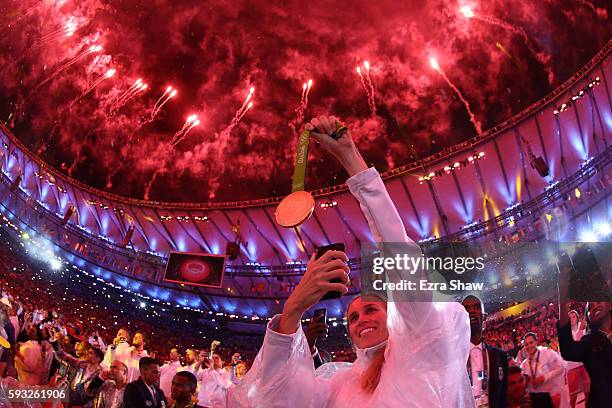 An athlete takes a photo of their medal as fireworks explode near the conclusion of the Closing Ceremony on Day 16 of the Rio 2016 Olympic Games at...