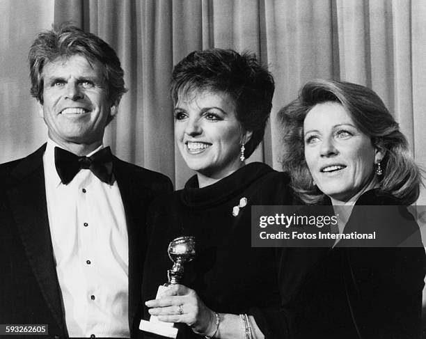 Actress Liza Minnelli holding her award for the television movie 'A Time to Live', with presenters William Devane and Patty Duke, at the Golden Globe...