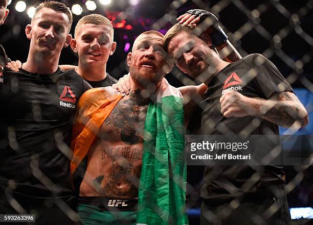 Conor McGregor of Ireland celebrates with his coach John Kavanaugh and team after defeating Nate Diaz in their welterweight bout during the UFC 202...