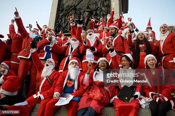 Large mob of bawdy Santas pose for a group photograph and sing their own unique Christmas carols at Nelson's Column in Trafalgar Square during the...