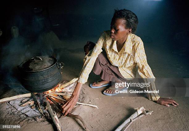 Two months after starting her ARV medication, HIV-Positive mother Nomphilo Mazuza cooks and warms herself on an indoor kitchen fire. She had begun...