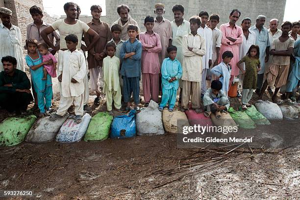 Residents of Miyan Motan village watch the water level slowly rise at a barrier of sandbags that they had put down to try keep floodwaters out of the...