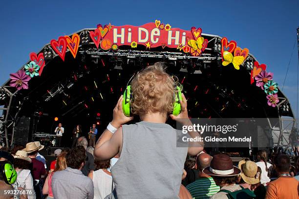 Young boy wears hearing defenders, also known as hearing protection earphones as he enjoys a performance by the energetic fold band Bellowhead at...
