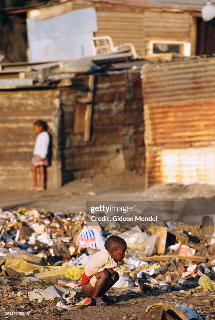 A poor black child crouches to defecate in a garbage pile outside ...
