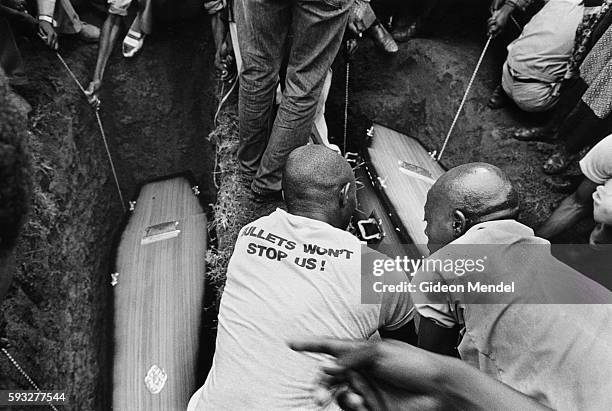 Caskets are lowered into graves during a funeral for the 11 victims of the Queenstown Massacre who were shot by police on November 17th in...