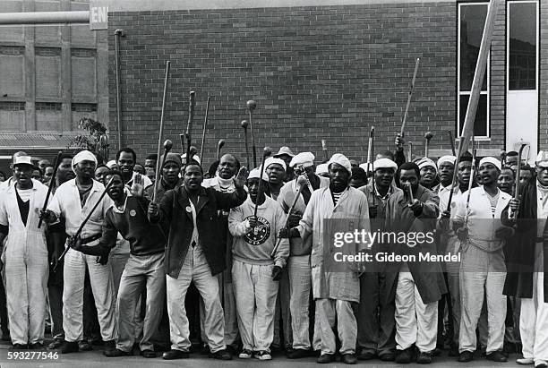 Factory workers raise sticks and clubs in protest during a workers strike outside a factory in Durban, South Africa.