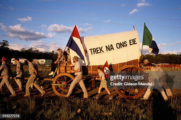 Historical reenactors participate in a reenactment of the Great Trek in South Africa. Flags of the Afrikaner Resistance Movement , and Transvaal are...