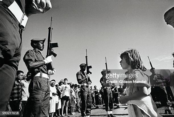 Young white girl watches black soldiers from the Namibian 101 battalion perform a drill, in Cape Town, South Africa, during festivities celebrating...