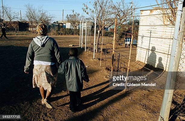 Matshaidiso Madondo, an HIV-positive 29-year-old widow, whose husband died from AIDS-related infections walks her 5-year-old son Siphisihle to school...