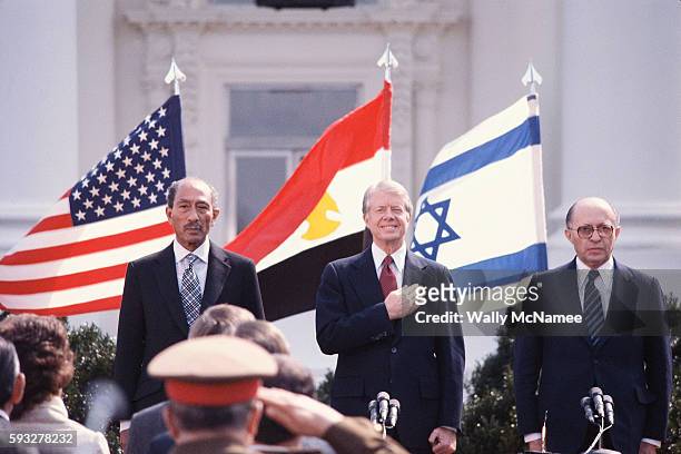President Jimmy Carter with Egyptian President Anwar Sadat and Israeli Prime Minister Menachem Begin stand during the playing of national anthems on...